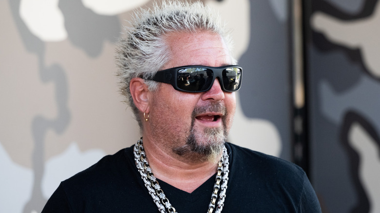 Chef Guy Fieri wearing sunglasses, a black shirt and chains around his neck