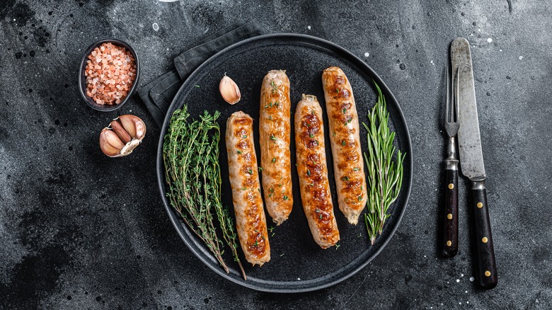 Bratwurst on dark plate with herbs