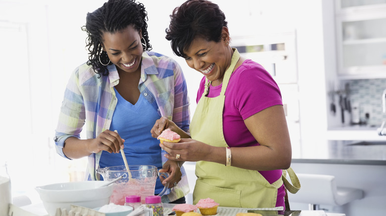 Women frosting pink cupcakes