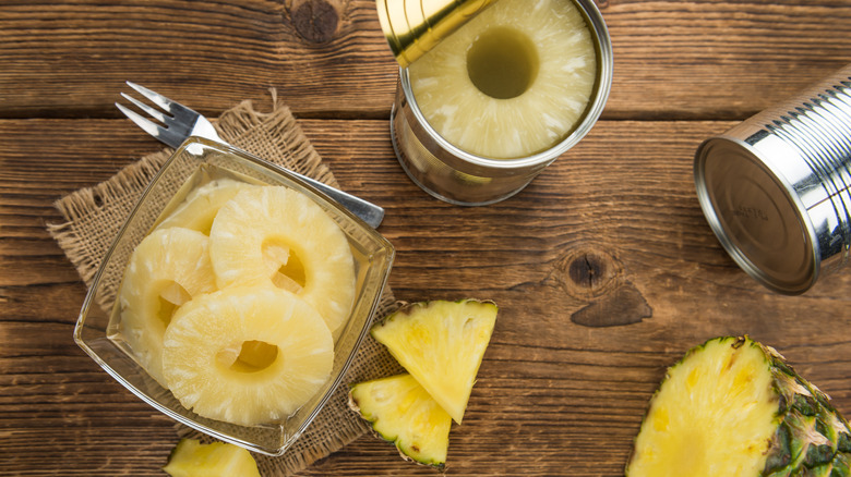 Opened can of pineapple rings next to a bowl of pineapple rings