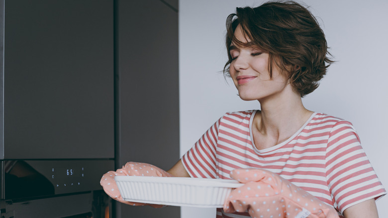 woman taking dish out of the oven
