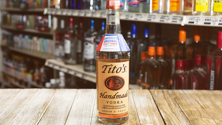 a bottle of Tito's vodka set on a wood bar