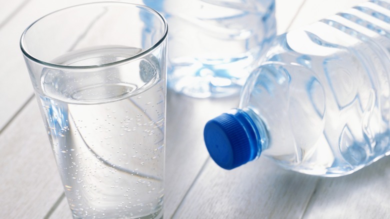 A pint glass of water and two plastic water bottles