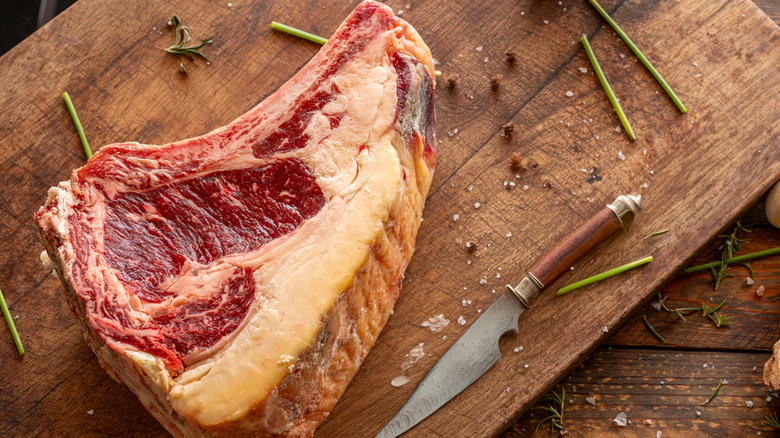 raw steak with a buttery yellow colored fat cap on a cutting board