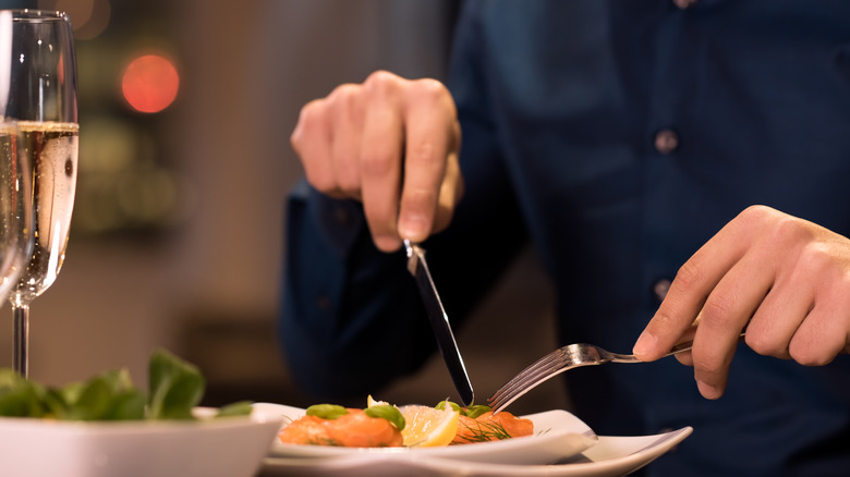 Man cutting into plate of salmon