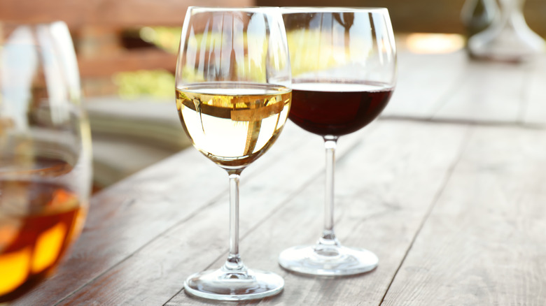 Glasses of red and white wine sit on a table