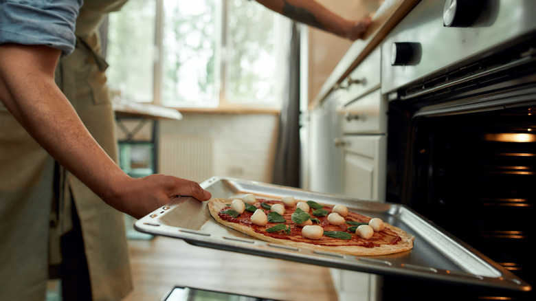 putting pizza in oven