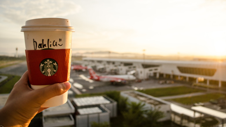 Hand holding up a Starbucks cup