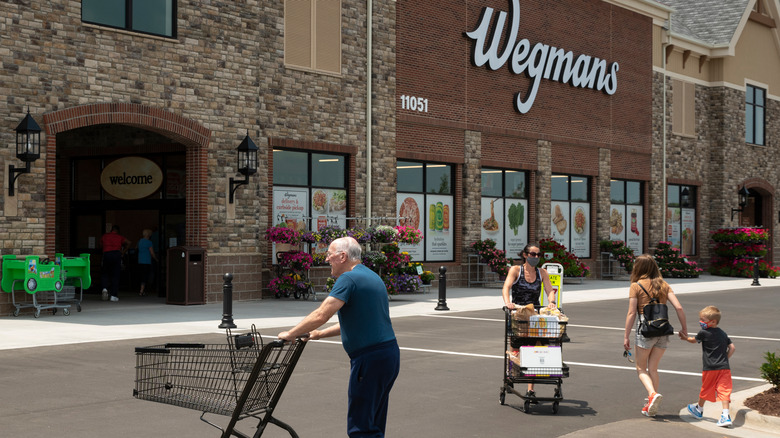 A man pushes a shopping cart outside Wegmans