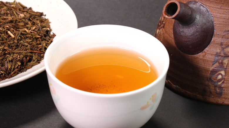 filled teacup, pot, and tea leaves