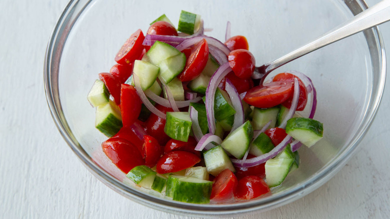 tomato, cucumber, onion in bowl with dressing