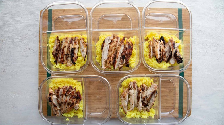five meal prep containers with sliced chicken and rice
