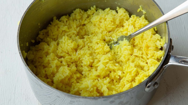 fluffing turmeric rice with fork