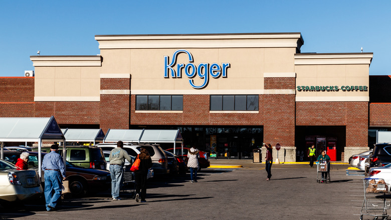 Entrance of Kroger with people in parking lot on a sunny day