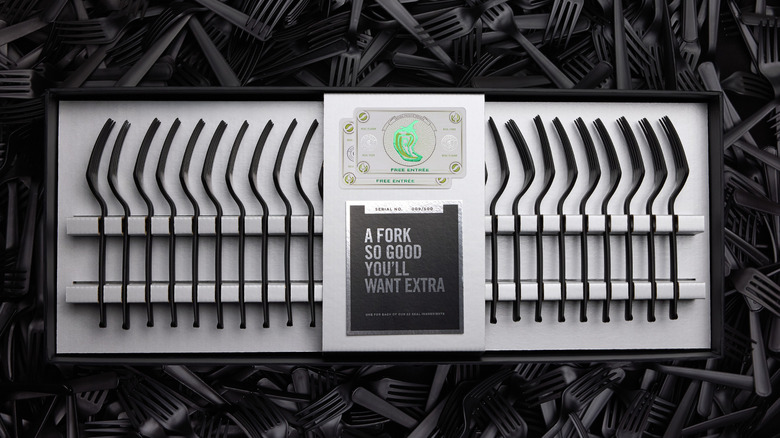 A top-down view of the fork collection box, on a background of even more black plastic forks