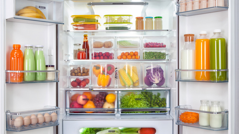 Open refrigerator with clear plastic organizers full of produce