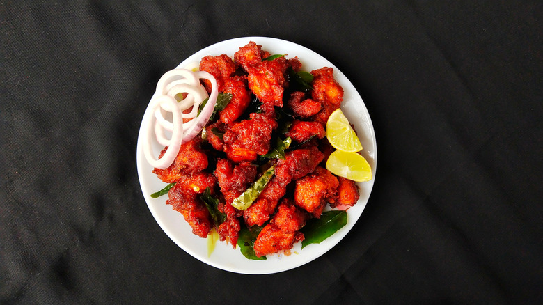 Indian fried chicken on white plate with onions