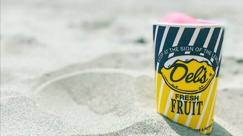 Cup reading "Del's" in sand
