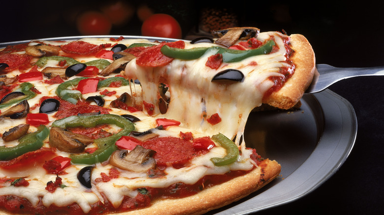 Person lifting pizza slice with fork