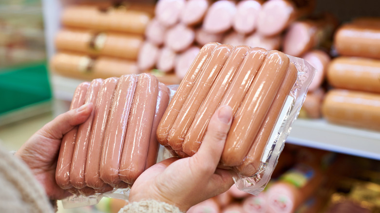 Hands hold hot dog packages