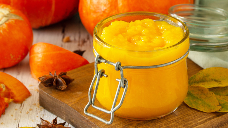 Pumpkin puree in jar in front of whole pumpkins
