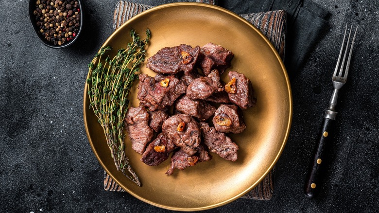 Cooked steak tips on gold plate 