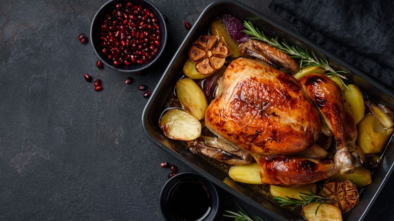 Roasted chicken on pan with potatoes and herbs