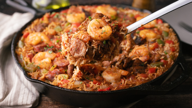 jambalaya in a cast iron skillet with a serving spoon