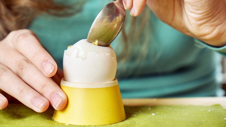woman eating an egg in a cup