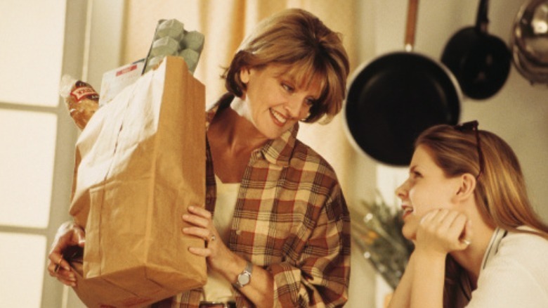 mother holding groceries near daughter