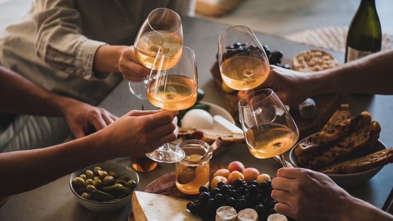 hands with wine glasses and charcuterie
