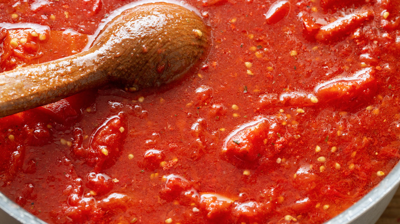 Bowl of red tomato sauce with wooden spoon
