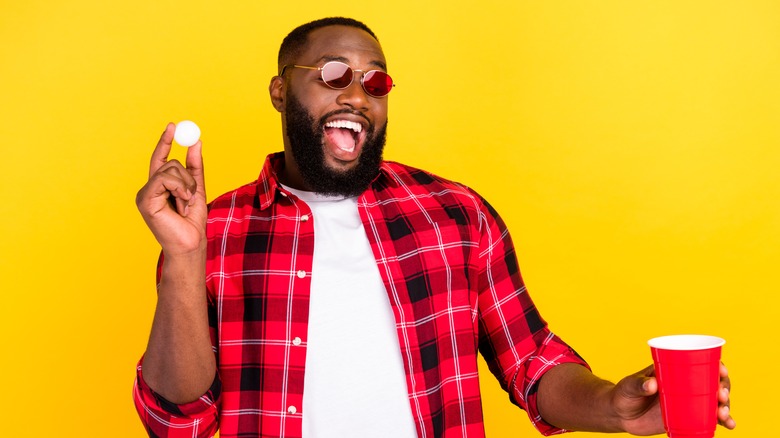 man holding cup and ping pong ball