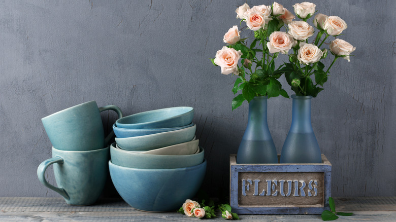 Decorative stack of mugs and bowls next to flower set