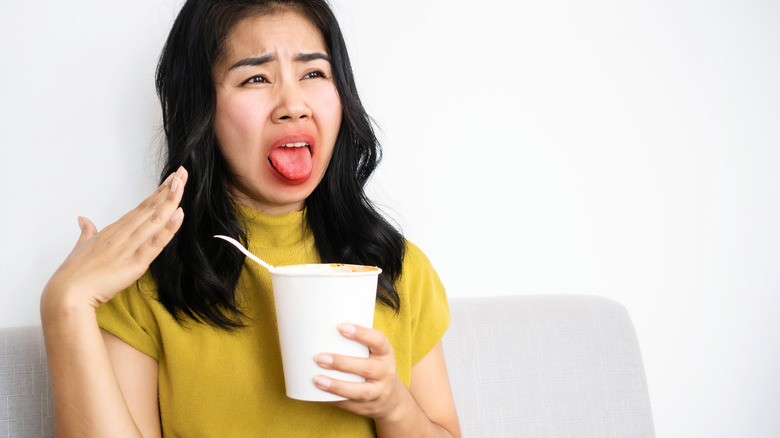 a woman burning mouth on instant ramen