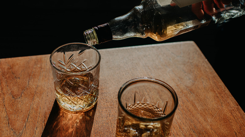 Pouring bourbon into two rocks glasses