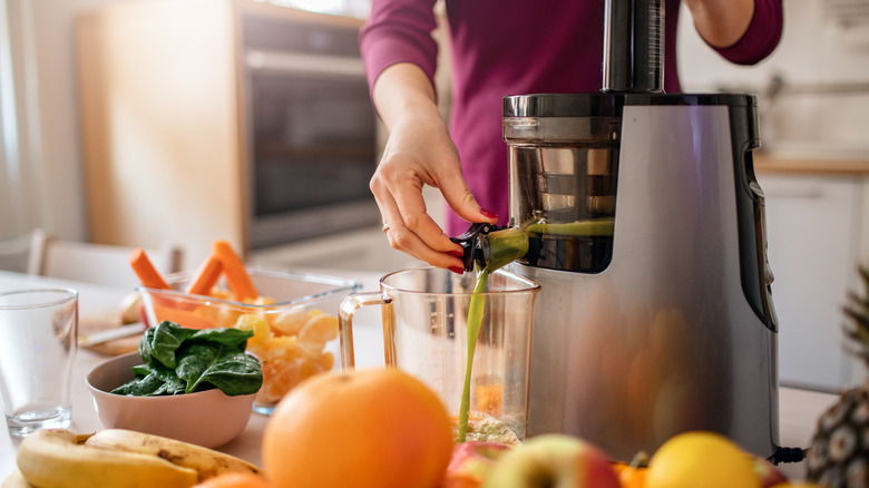 Green juice being poured into a pitcher from a juicer