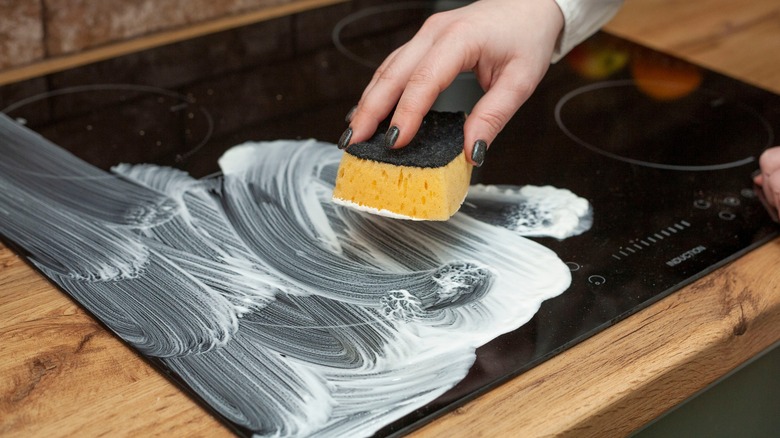 Woman cleaning an electric stovetop with baking soda