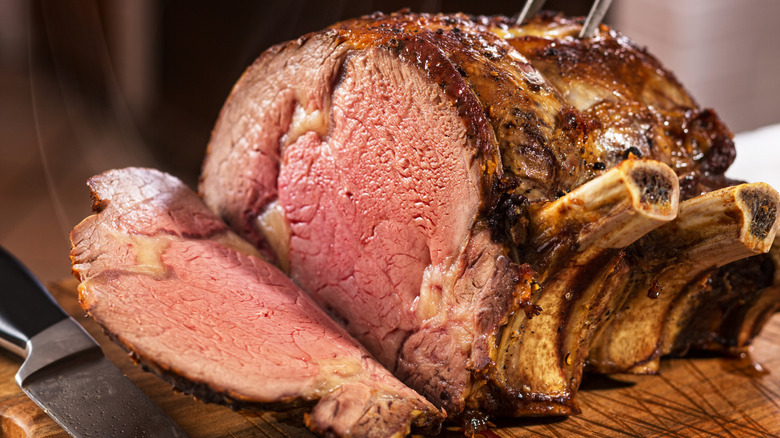 A medium-rare rib roast on a cutting board being carved