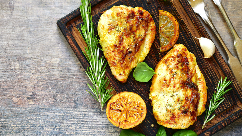cooked chicken breasts with rosemary on baord