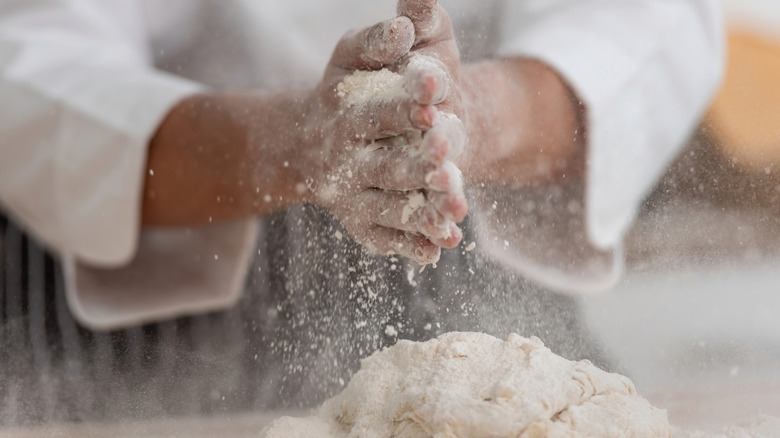 Flour on hands over dough
