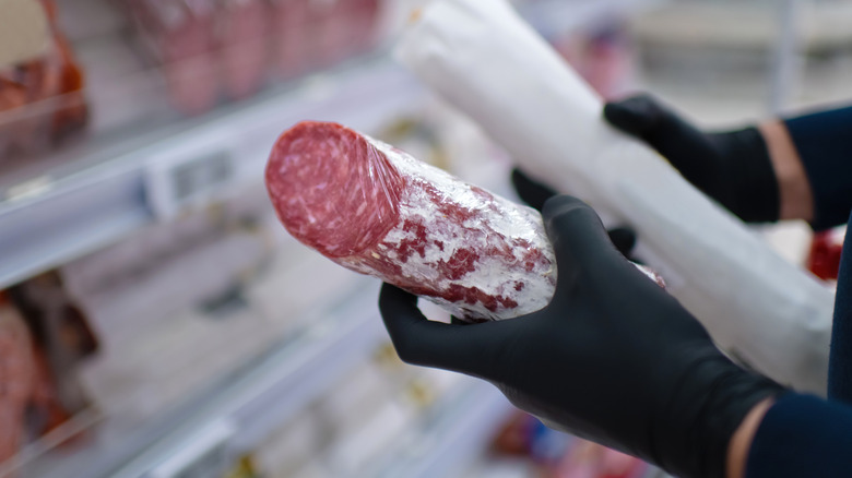 A woman shopping for deli meat at a supermarket.