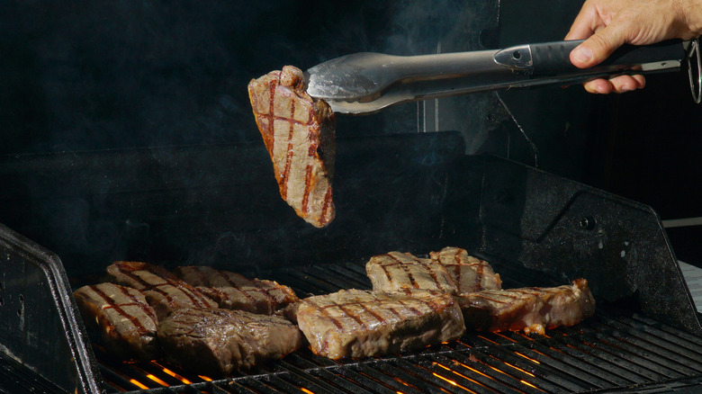 flipping steak on grill