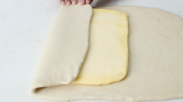 A person enclosing butter in dough