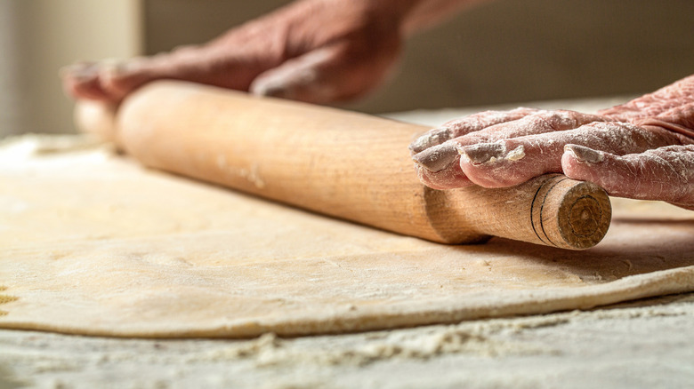 Person rolling out dough with a rolling pin
