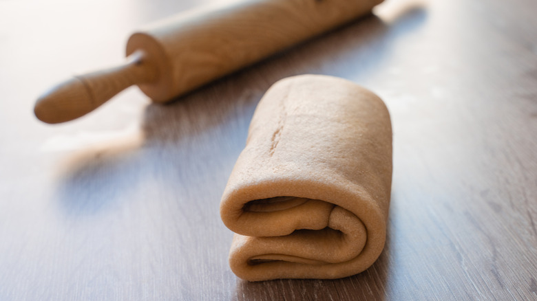 Laminated dough and a rolling pin on a wooden table