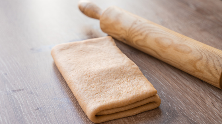 Laminated dough and a rolling pin on a wooden table