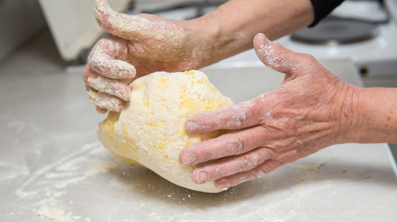 A person kneading dough with their hands