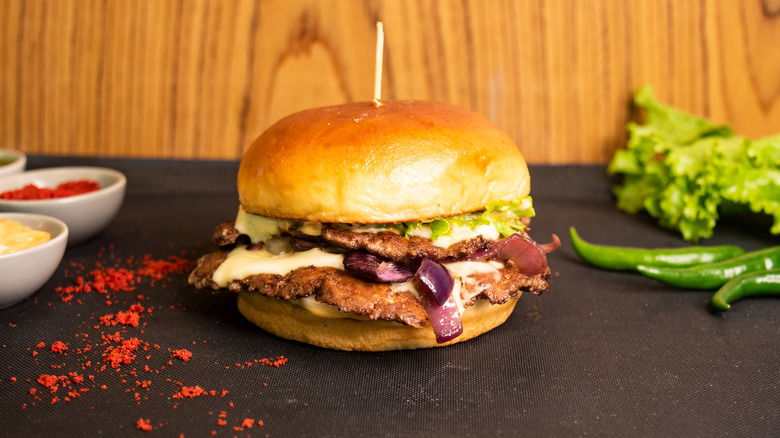 A smash burger topped with cheese and red onion