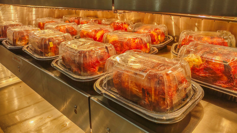 Rows of packaged rotisserie chickens in a warmer from a grocery store